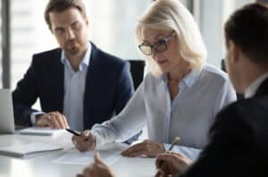 Concentrated aged businesswoman checking agreement before signing