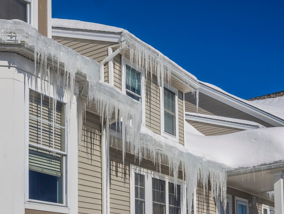 Ice dams and snow on roof and gutters of a residential property.