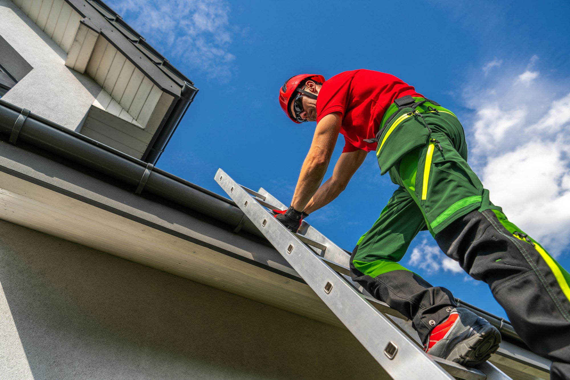 Professional Maintenance Worker Climbing a Ladder to Repair Roof Gutter on a Sunny Day | LoPriore Insurance Agency Professional Maintenance Worker Climbing a Ladder to Repair Roof Gutter on a Sunny Day