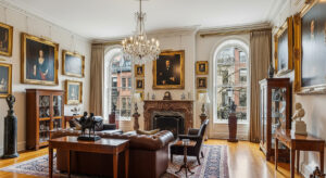 Luxurious Boston-area living room showcasing high-value assets including oil paintings in ornate gold frames, crystal chandelier, antique furniture, oriental rugs, and collectible items displayed in mahogany cabinets